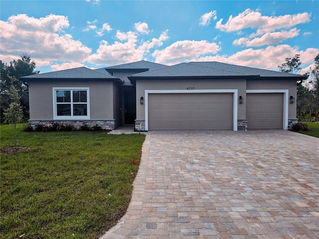 prairie-style house with a garage, decorative driveway, a front lawn, and stucco siding