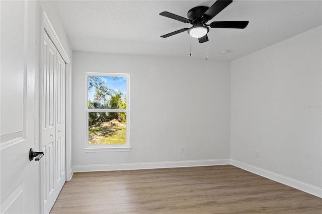 unfurnished bedroom featuring light wood finished floors, ceiling fan, baseboards, and a closet