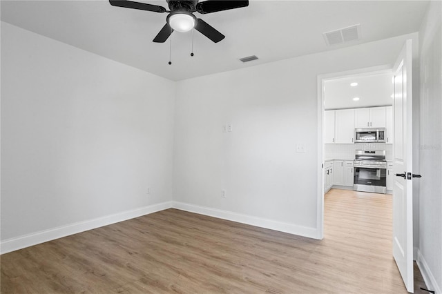 unfurnished room featuring light wood-type flooring, visible vents, baseboards, and a ceiling fan