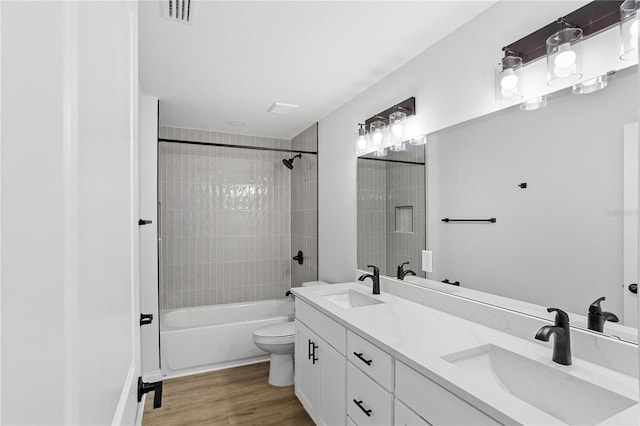 bathroom with visible vents, toilet, wood finished floors, and a sink