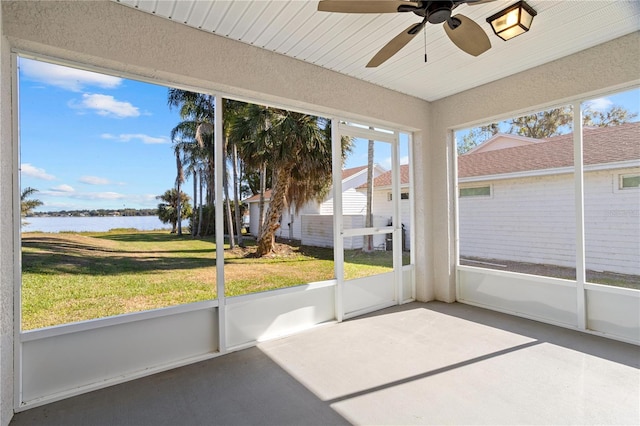 unfurnished sunroom featuring ceiling fan and a water view