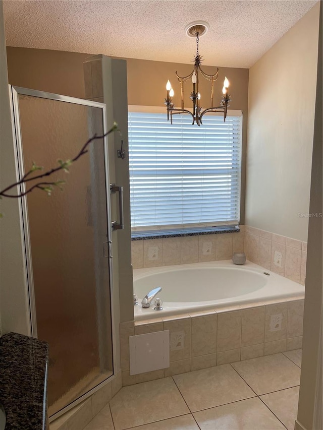 bathroom featuring an inviting chandelier, a bath, a shower stall, and tile patterned flooring