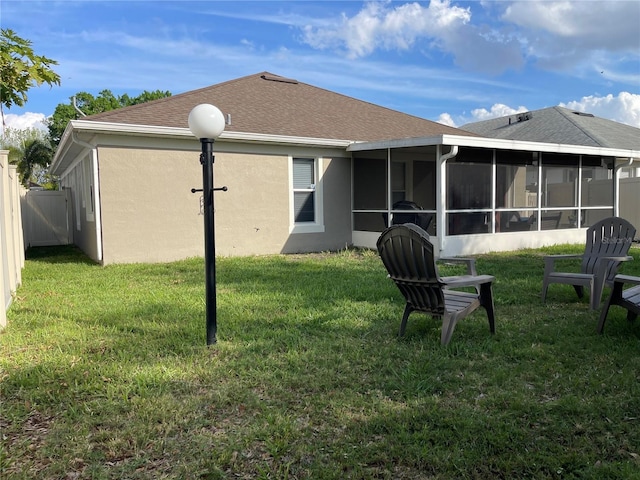 rear view of house featuring a lawn, a sunroom, and stucco siding