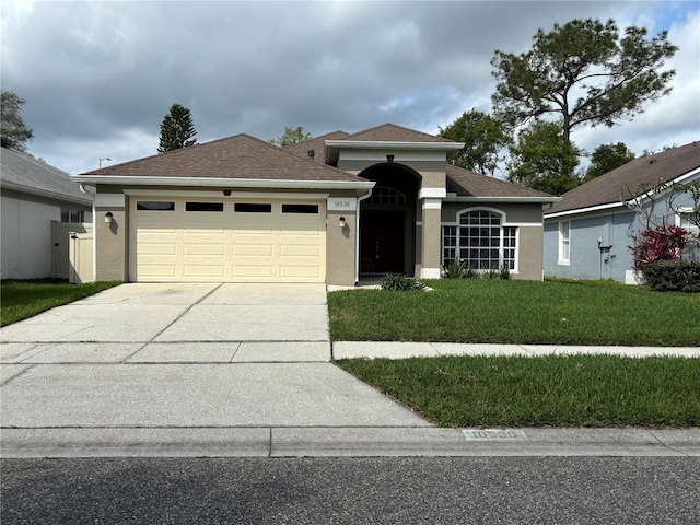 view of front of house featuring a shingled roof, concrete driveway, a front yard, stucco siding, and an attached garage