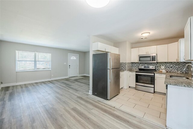5210 Grandview Dr, Orlando, FL 32808 - kitchen featuring light stone countertops, decorative backsplash, white cabinets, stainless steel appliances, and a sink