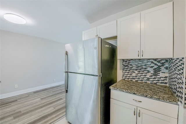 5210 Grandview Dr, Orlando, FL 32808 - kitchen featuring baseboards, decorative backsplash, dark stone countertops, freestanding refrigerator, and white cabinets