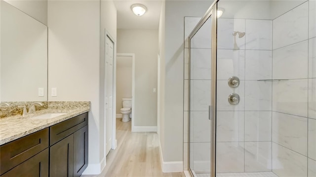 full bath featuring a shower stall, toilet, vanity, and baseboards