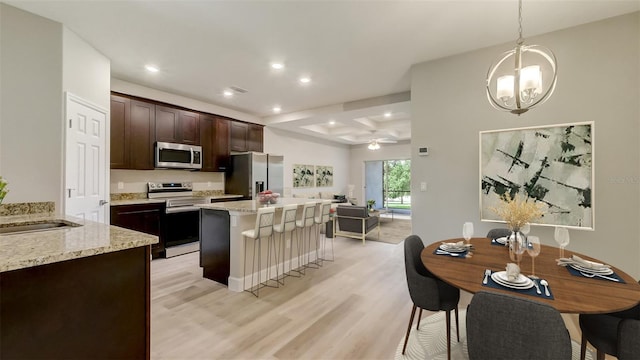 kitchen featuring light wood finished floors, a center island, dark brown cabinetry, recessed lighting, and stainless steel appliances