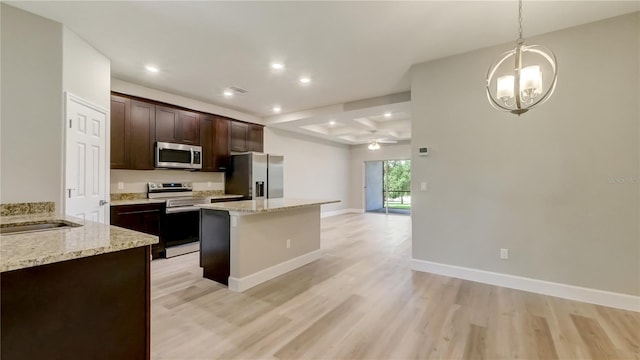 kitchen featuring dark brown cabinets, a kitchen island, light wood-type flooring, ceiling fan with notable chandelier, and stainless steel appliances