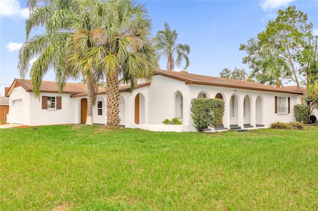 mediterranean / spanish house with stucco siding, a garage, and a front lawn