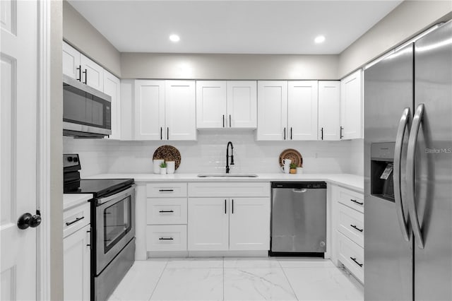 kitchen with tasteful backsplash, light countertops, white cabinets, stainless steel appliances, and a sink