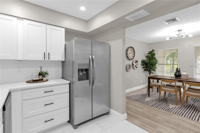 kitchen featuring visible vents, stainless steel appliances, light countertops, white cabinets, and tasteful backsplash