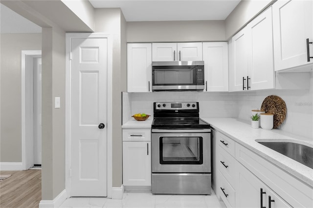 kitchen with baseboards, stainless steel appliances, white cabinets, marble finish floor, and tasteful backsplash