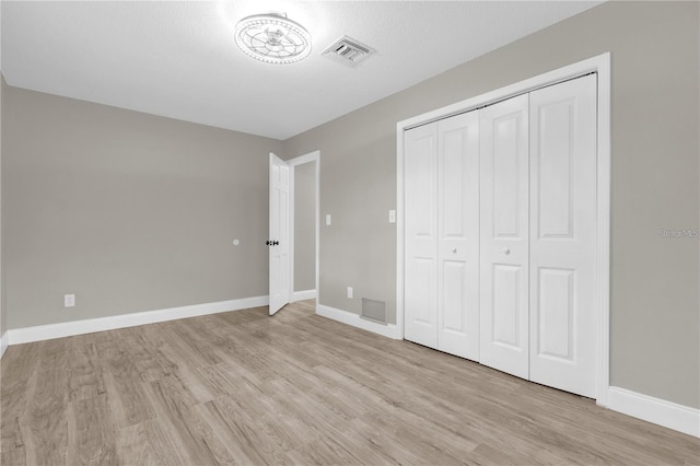 unfurnished bedroom featuring a closet, visible vents, light wood-type flooring, and baseboards