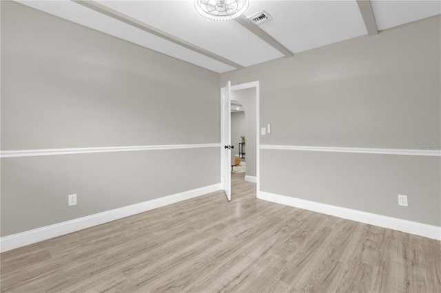 unfurnished room with light wood finished floors, visible vents, beamed ceiling, and baseboards