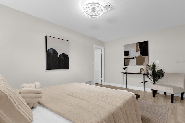 bedroom featuring visible vents, baseboards, and wood finished floors