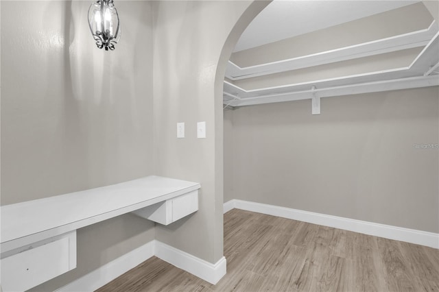 spacious closet with arched walkways and light wood-type flooring