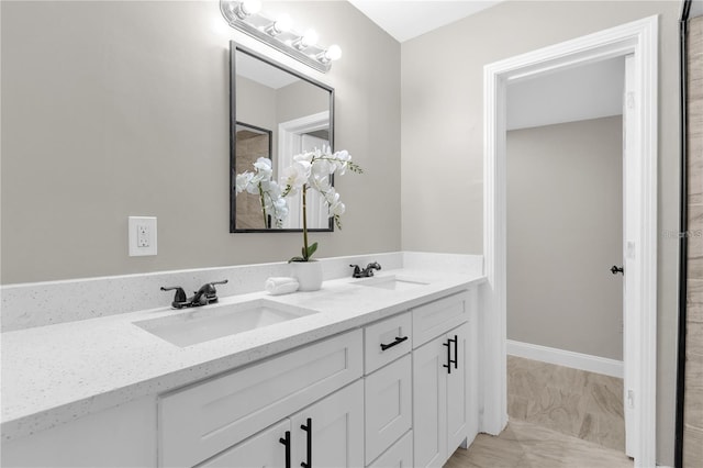 bathroom with double vanity, baseboards, and a sink