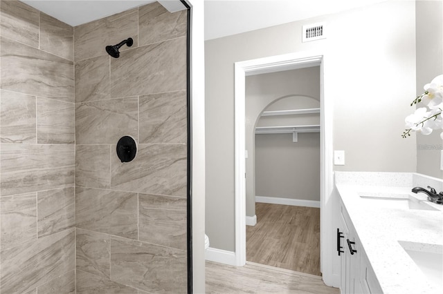 bathroom featuring a sink, visible vents, baseboards, and a tile shower