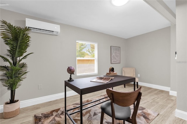 office area featuring light wood-style flooring, a wall mounted air conditioner, and baseboards