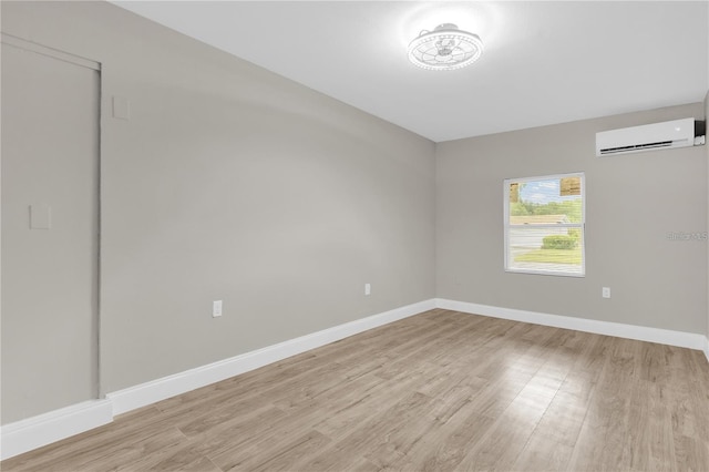 empty room with baseboards, light wood-style floors, and an AC wall unit