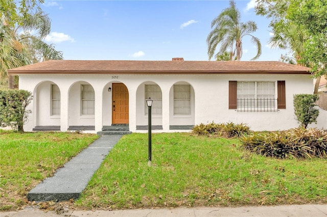 view of front of house featuring covered porch, stucco siding, and a front yard