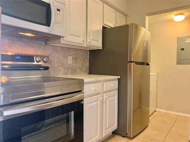 kitchen with electric panel, decorative backsplash, light tile patterned floors, appliances with stainless steel finishes, and white cabinetry