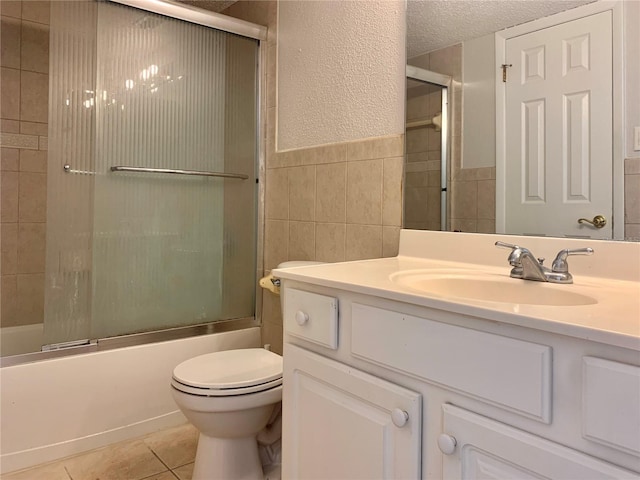 full bath with vanity, a textured ceiling, tile walls, combined bath / shower with glass door, and tile patterned floors