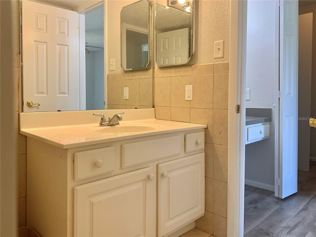 bathroom with tile walls, vanity, and wood finished floors