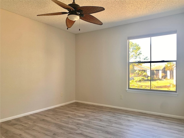 unfurnished room featuring baseboards, plenty of natural light, a textured ceiling, and wood finished floors