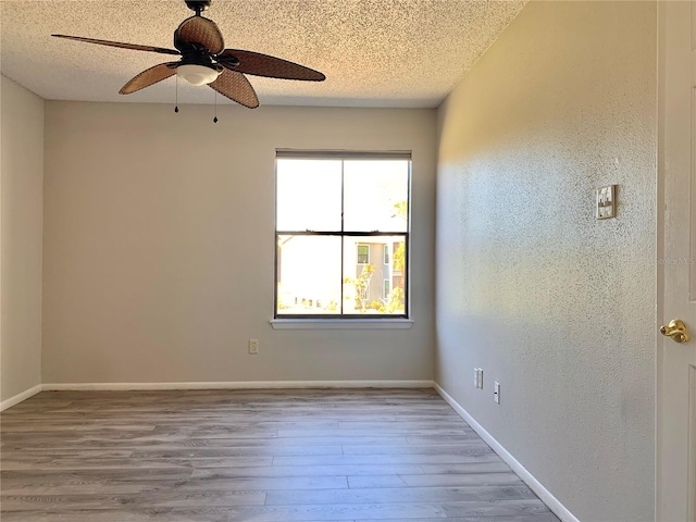 unfurnished room featuring a ceiling fan, wood finished floors, baseboards, a textured ceiling, and a textured wall