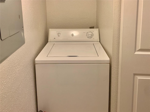 washroom featuring washer / dryer, laundry area, and a textured wall