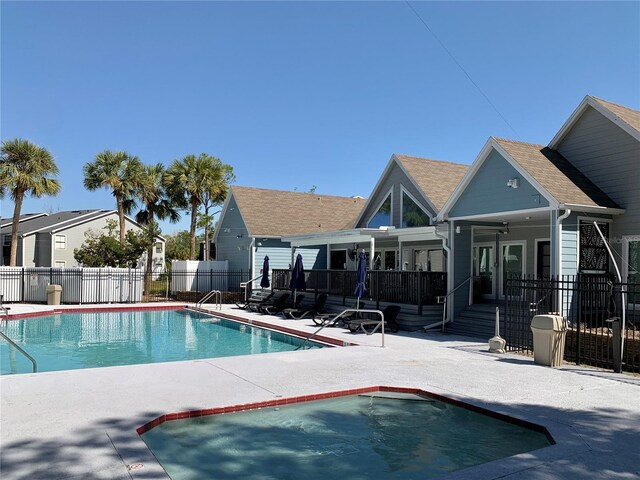 community pool with fence, a deck, and a patio area