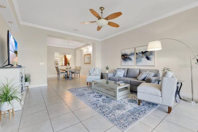 living area with light tile patterned floors, baseboards, crown molding, and ceiling fan with notable chandelier