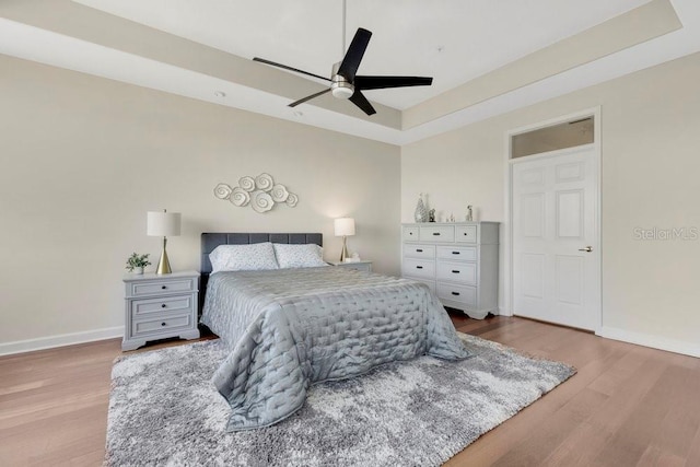 bedroom with a ceiling fan, baseboards, and wood finished floors