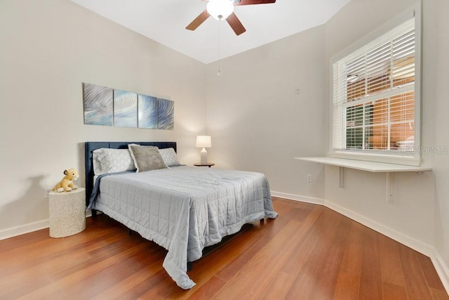 bedroom featuring baseboards, wood finished floors, and a ceiling fan