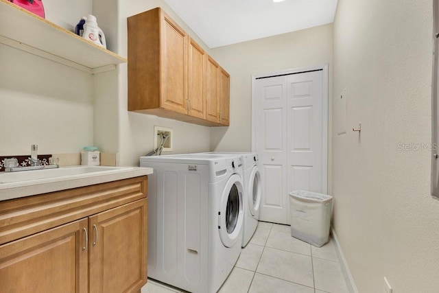 laundry area with washing machine and clothes dryer, light tile patterned floors, cabinet space, and baseboards