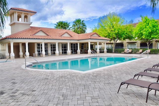 community pool with a patio and fence