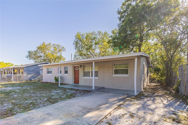 ranch-style home featuring fence, a front yard, and concrete block siding