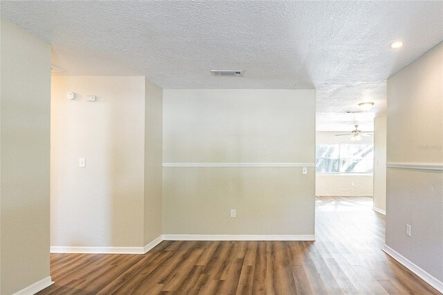 unfurnished room featuring wood finished floors, a textured ceiling, ceiling fan, baseboards, and visible vents