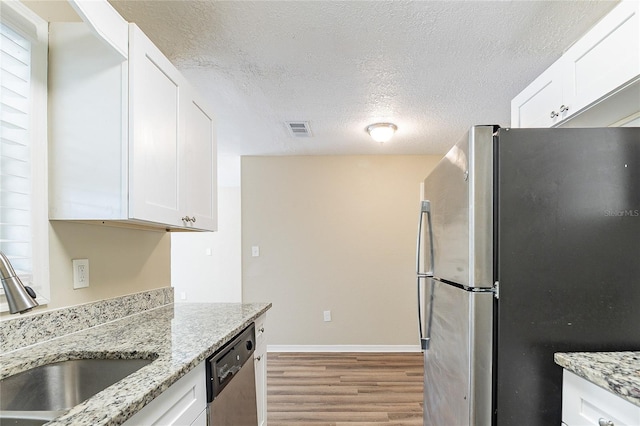 kitchen with stainless steel appliances, light wood-style flooring, a sink, a textured ceiling, and visible vents