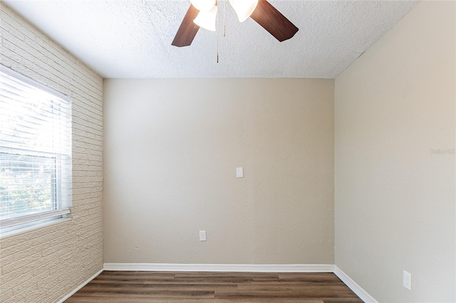 unfurnished room featuring a ceiling fan, baseboards, a textured ceiling, and dark wood-style flooring