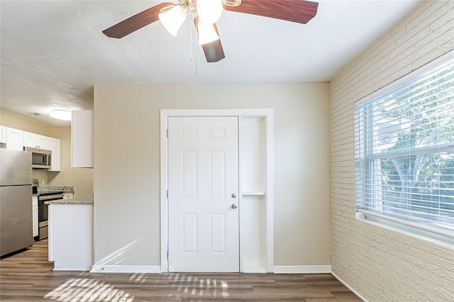 interior space with a ceiling fan, baseboards, a healthy amount of sunlight, and wood finished floors