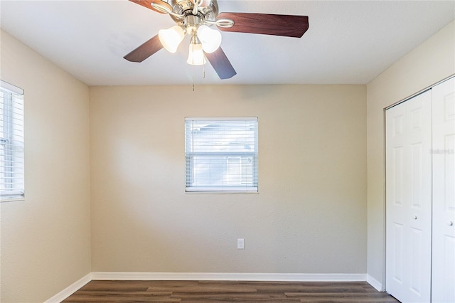 unfurnished bedroom featuring dark wood finished floors, baseboards, ceiling fan, and a closet