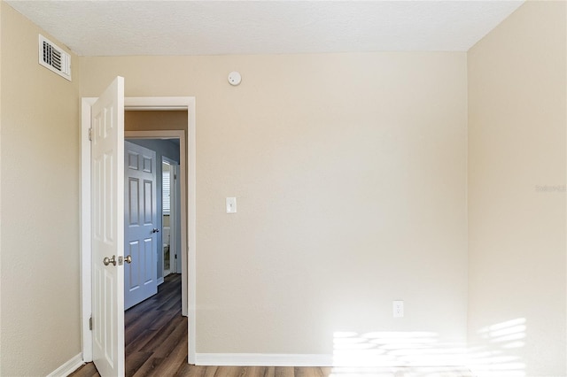 spare room featuring baseboards, wood finished floors, and visible vents