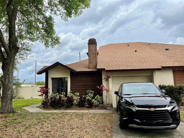 ranch-style house featuring stucco siding, driveway, fence, roof with shingles, and a garage