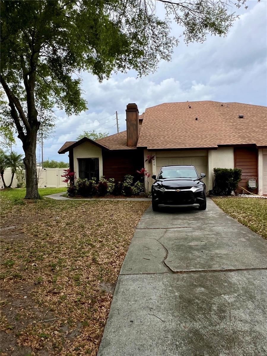 view of side of home with a chimney, an attached garage, and concrete driveway