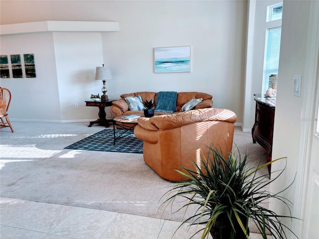 living room with light tile patterned floors, light colored carpet, and baseboards