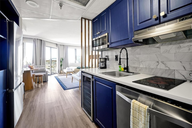 kitchen with wine cooler, open floor plan, appliances with stainless steel finishes, blue cabinets, and a sink