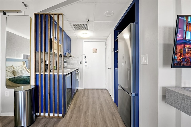 hall featuring a drop ceiling, light wood-style flooring, visible vents, and a sink